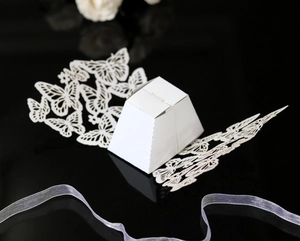 Detailed laser-cut butterfly design on white paper wedding favor box on black surface