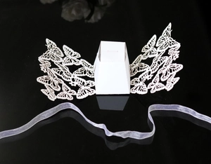 Macro detail of laser-cut white wedding candy box with butterfly design and silk ribbon