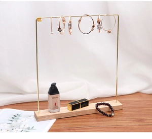 Detail of gold metal necklace holder with natural wood base on white fabric background