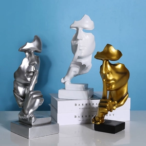 Three creative resin Silence is Golden sculptures in silver, white, and gold on desk