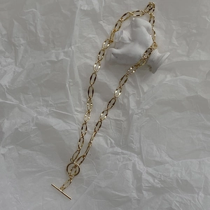 Detailed close-up of a gold chunky link chain necklace with a vintage OT buckle closure
