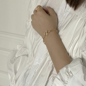 Close-up of a gold OT buckle chain bracelet and matching ring on a model's wrist