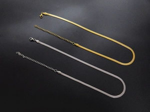 Detail of flat snake bone chain necklaces in gold and silver finish with lobster clasp