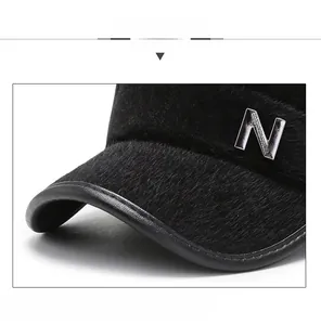 Detail of plush black winter flat cap featuring leather trim and silver metal N emblem