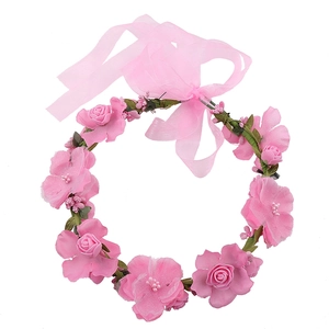 Close-up of pink artificial roses and delicate green leaves on a floral headband