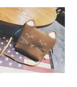 Detail of a brown suede cat-shaped crossbody bag with white cat face embroidery