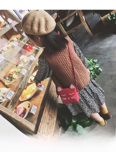 Rear view of a child wearing a cute red cat-shaped crossbody bag in a cozy cafe setting