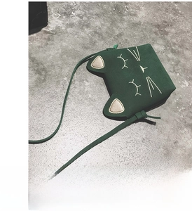 Detail view of a dark green cat-shaped crossbody bag with cute ear design and embroidery