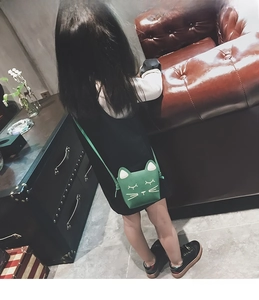 Green cat shaped PU leather crossbody bag for kids shown on child back view in room