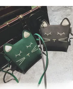 Detail of cartoon cat-ear crossbody bags in green and dark grey suede material