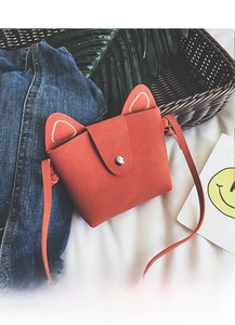 Close-up of cute cat-ear shaped mini crossbody bag in brick red suede with magnetic clasp