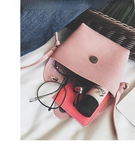Flat lay of pink suede mini crossbody bag showing interior with daily essentials