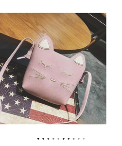 Close-up of pink cat-shaped shoulder bag with cute embroidery and 3D ears on wood surface