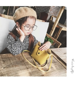 Cute bright yellow cat-ear shoulder bag shown as worn by a young girl in a cafe