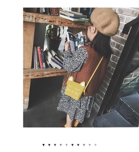 Girl wearing a cute yellow cartoon cat crossbody bag over a floral dress in library