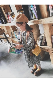 Girl wearing floral dress and knit vest with cat-shaped yellow crossbody bag and beret