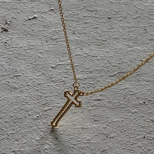 Vintage 925 sterling silver hollow cross pendant with gold finish on textured background