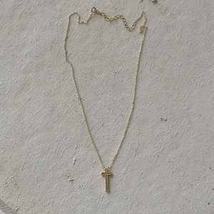Detail of golden cross pendant with milgrain texture and adjustable fine chain link