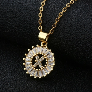 Détail macro du pendentif lettre X dorée serti de zircons sur cuir noir texturé