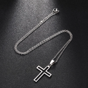 Detailed view of a silver hollow cross pendant with a minimalist chain on black texture