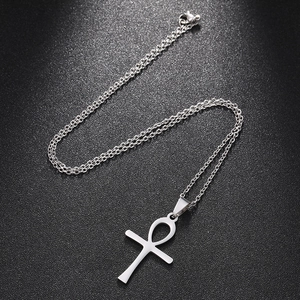 Macro detail of silver stainless steel Ankh cross pendant on a textured dark surface