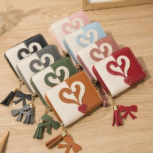 Short zipper wallet for women with heart patch and tassel bow on wooden table