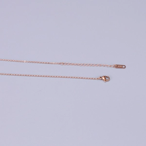 Close-up of the K18 certification stamp on a rose gold titanium steel necklace chain