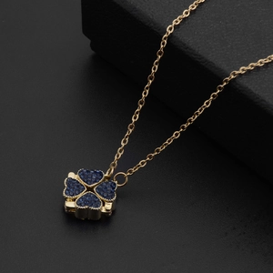Close-up of a four-leaf clover necklace with blue heart gems in a black jewelry gift box