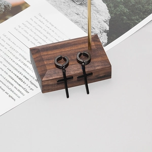 Minimalist black stainless steel cross earrings on a wooden stand with a card detail