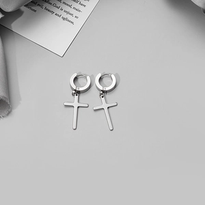 Polished silver stainless steel cross pendant earrings displayed on gray fabric