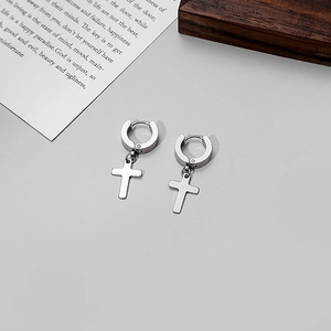 Detailed view of polished stainless steel silver cross charm earrings on a minimalist background