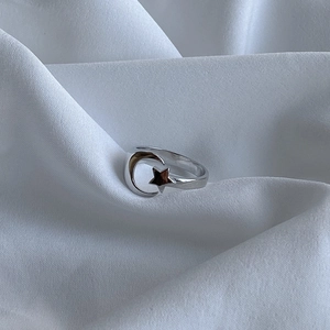 Detail of a minimalist 925 silver star and moon ring on a white silk background