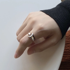 Detail shot of a silver star and moon relief ring worn on a finger with knit texture