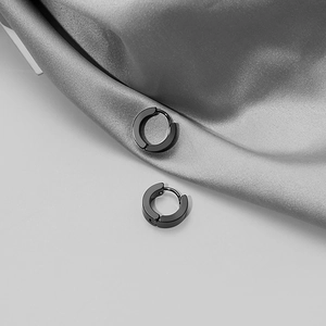Classic pair of matte black stainless steel hoop earrings on elegant silk fabric