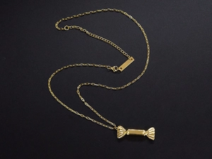 Detailed close-up of a golden candy-shaped pendant on a fine titanium steel link chain