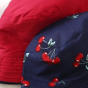Detail of red cotton fabric and blue cherry print on reversible children's sun hats