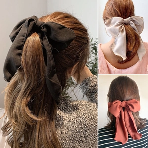 Elegant fabric bow hair ties in black, beige, and brick red shown on long hair