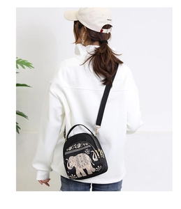Rear view of a black waterproof nylon crossbody bag with elephant embroidery and adjustable strap