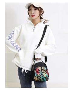 Woman carrying a black water-resistant nylon bag with colorful leaf patterns for outdoor use
