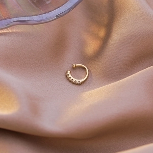 Detail of gold C-shaped ear cuff with pave-set cubic zirconia on champagne satin