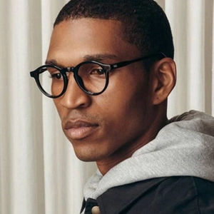 Close-up of vintage black round metal glasses on a model with a soft fabric background