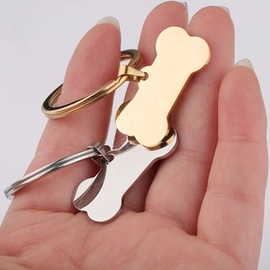 Polished bone-shaped stainless steel pet ID tags in gold and silver held by hand