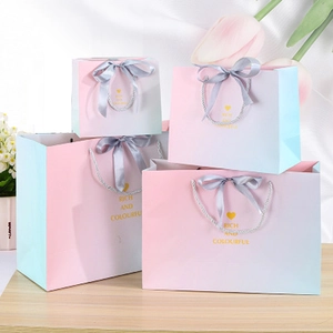 Pink gradient gift bags with silver ribbon handles and gold rich and colorful print