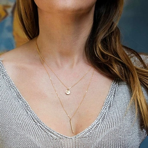 Detail of layered gold stainless steel necklace with round crystal and rectangular pendants