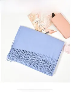 Macro detail of sky blue cashmere-like scarf showing soft texture and tassel fringe