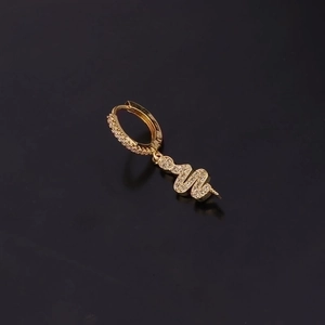 Golden snake-shaped earring with zircon crystals shown against a professional black background