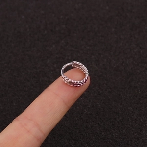 Three-row twisted silver ring hoop with a textured spiral design shown on fingertip