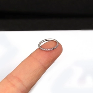 Minimalist silver stainless steel hoop ring with side-set zircons shown on a fingertip