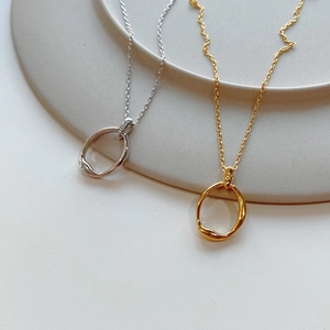 Close-up of irregular S925 sterling silver oval pendants in gold and silver finishes
