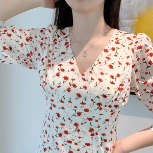 Close-up of minimalist geometric silver pendant necklace paired with floral print dress